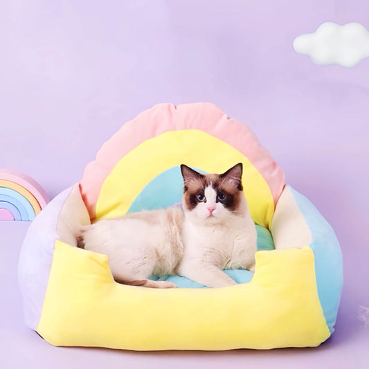 A cat is lying in a rainbow coloured sofa styled pet bed