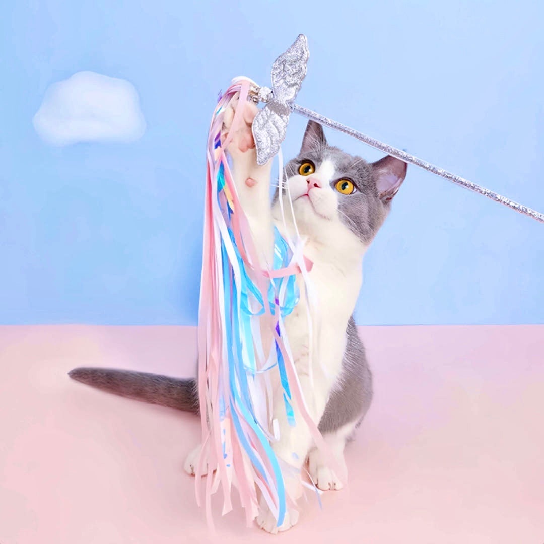 A cat is playing a fairy wing design cat teaser stick toy with bells